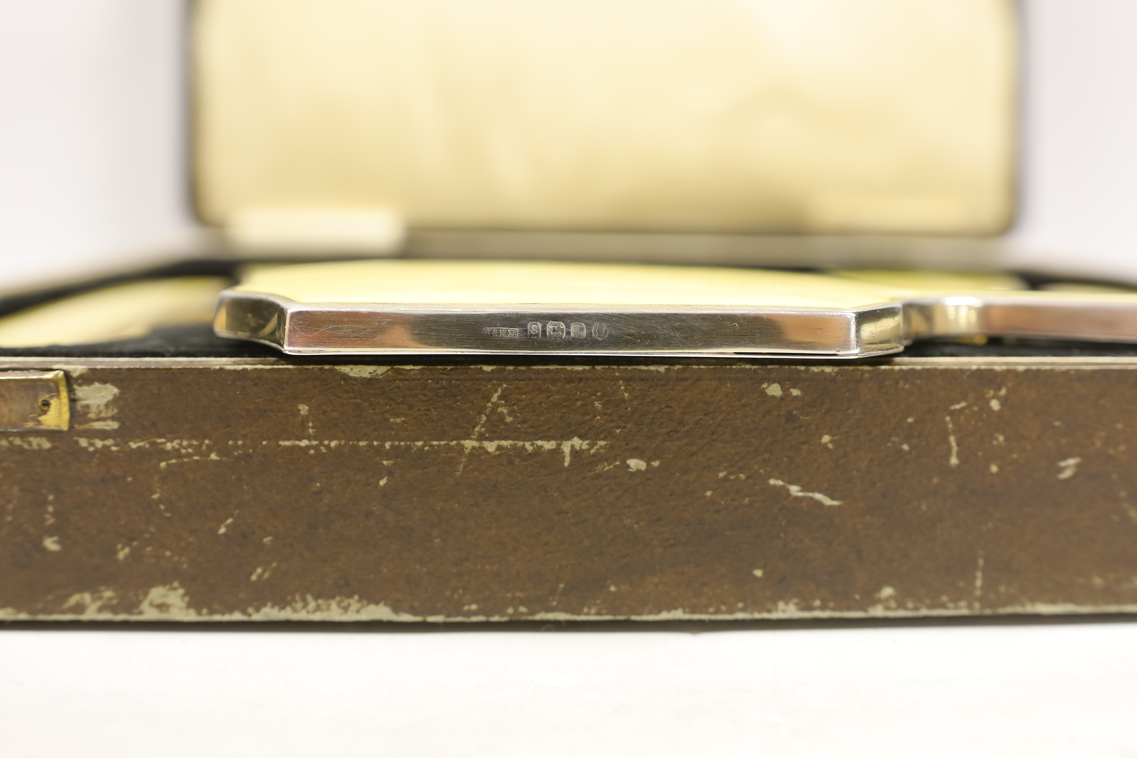 A cased George V silver and yellow guilloche enamel mounted five piece mirror and brush set, Hassett & Harper. Birmingham, 1935.